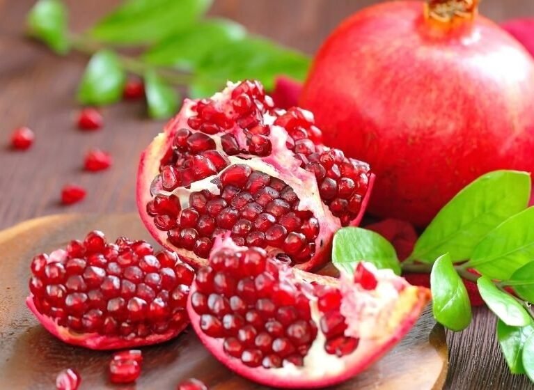 Natur markalı taze ve kaliteli narların şifalı sırları, kesilmiş nar taneleri ve bütün kırmızı nar.